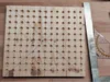 Lochplatte aus Holz mit Bleistiftmarkierungen und einem Anschlagwinkel