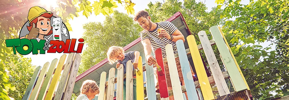 Drei Personen streichen einen Holzzaun mit Pinseln an.