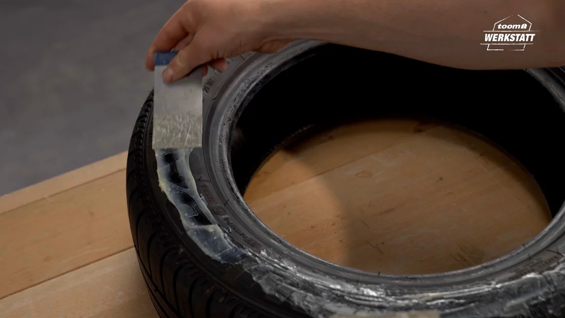 Person trägt Kleber auf Reifen auf