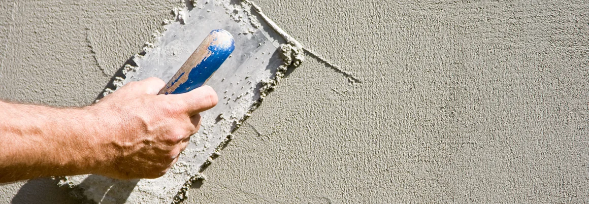 Person verputzt Wand mit Kelle