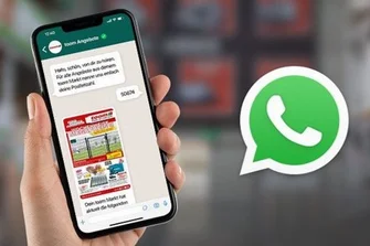 Hand hält Smartphone mit geöffnetem Chatverlauf und Prospekt