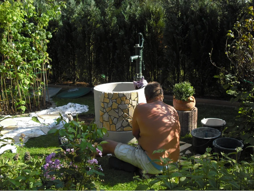 Person verkleidet einen Brunnen mit Steinen