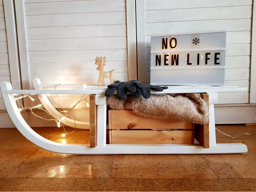 Weißer Holzschlitten mit Dekoration