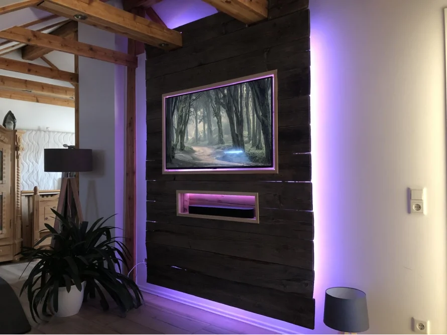 Fernseher an einer dunklen Holzwand mit lila Beleuchtung