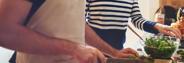 Zwei Personen schneiden Gemüse mit Messer.