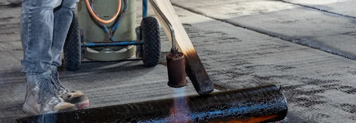 Person verklebt Dachpappe mit Brenner