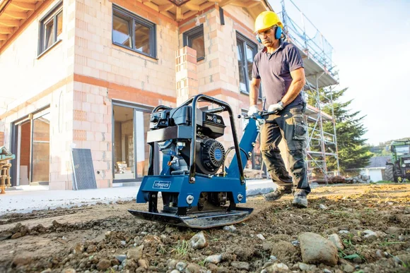 Person bedient Rüttelplatte auf Baustelle
