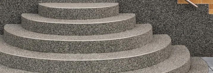 Gebogene Steintreppe vor einer Haustür.