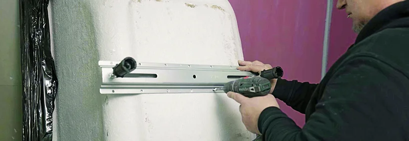 Person montiert Fußgestell an Badewanne