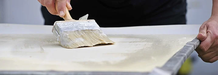 Person trägt Kleister mit Pinsel auf