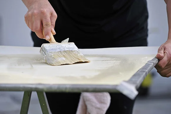 Person trägt Kleister mit Pinsel auf