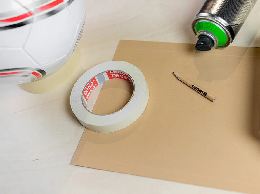 Klebeband, Stift und Sprühdose auf Pappe