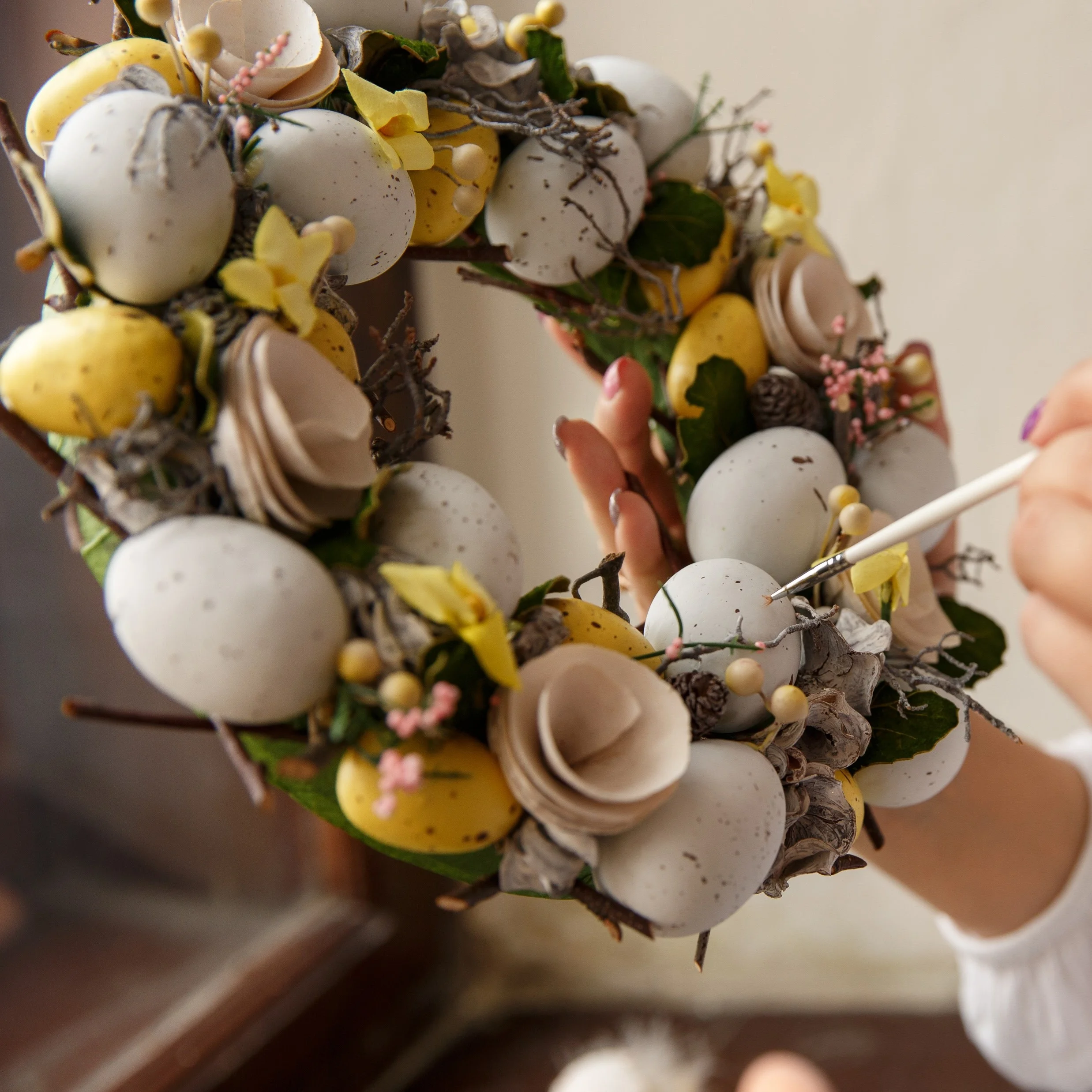 Person bemalt Ostereier auf Kranz