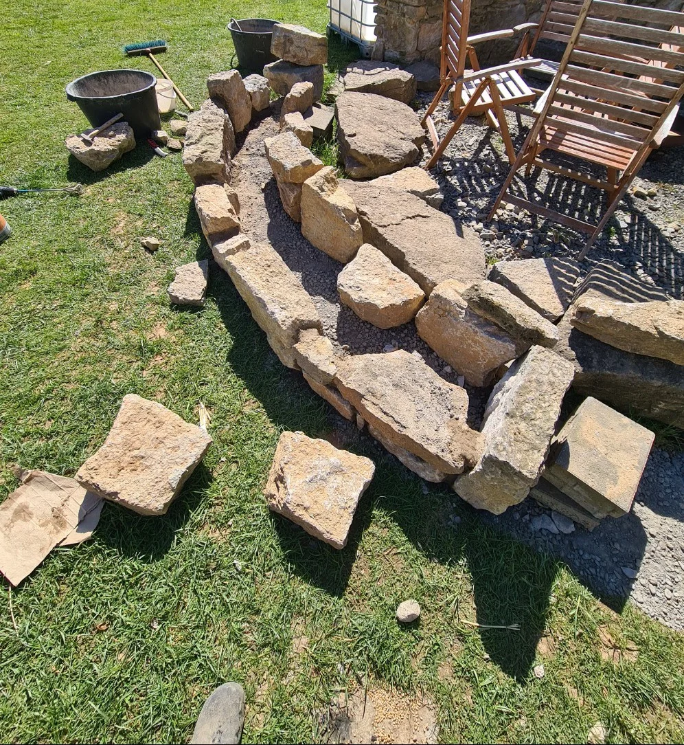 Bau einer geschwungenen Trockenmauer aus Naturstein im Garten