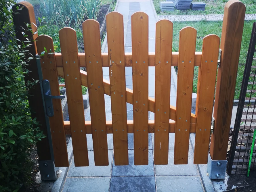 Ein Holzzaun mit offenem Gartentor.
