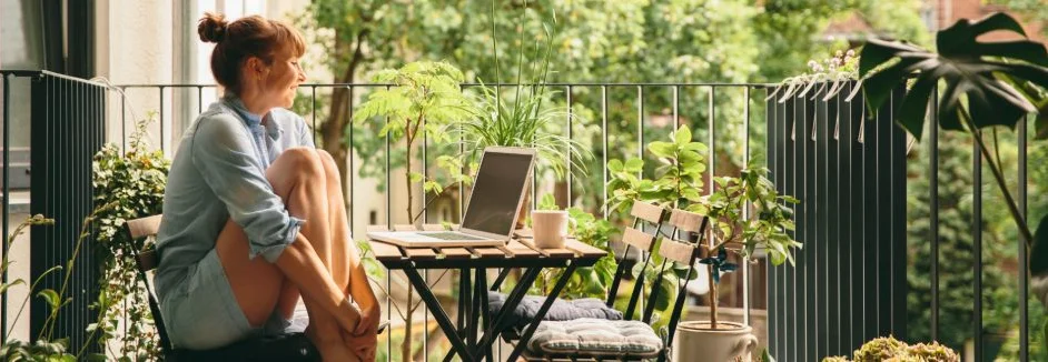 Person sitzt an einem Tisch auf einem Balkon