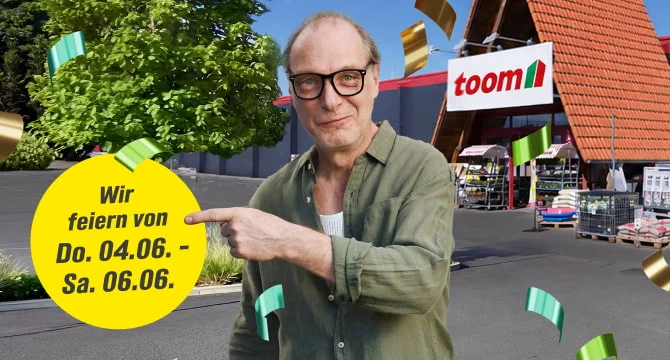 Mensch mit Brille feiert vor einem Baumarkt und zeigt auf eine Ankündigung.