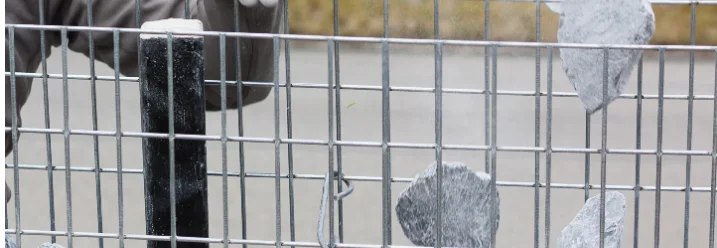 Person befüllt Gabione mit Steinen