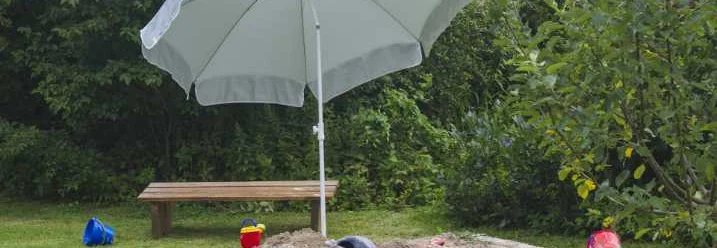 Sandkasten mit Sonnenschirm im Garten