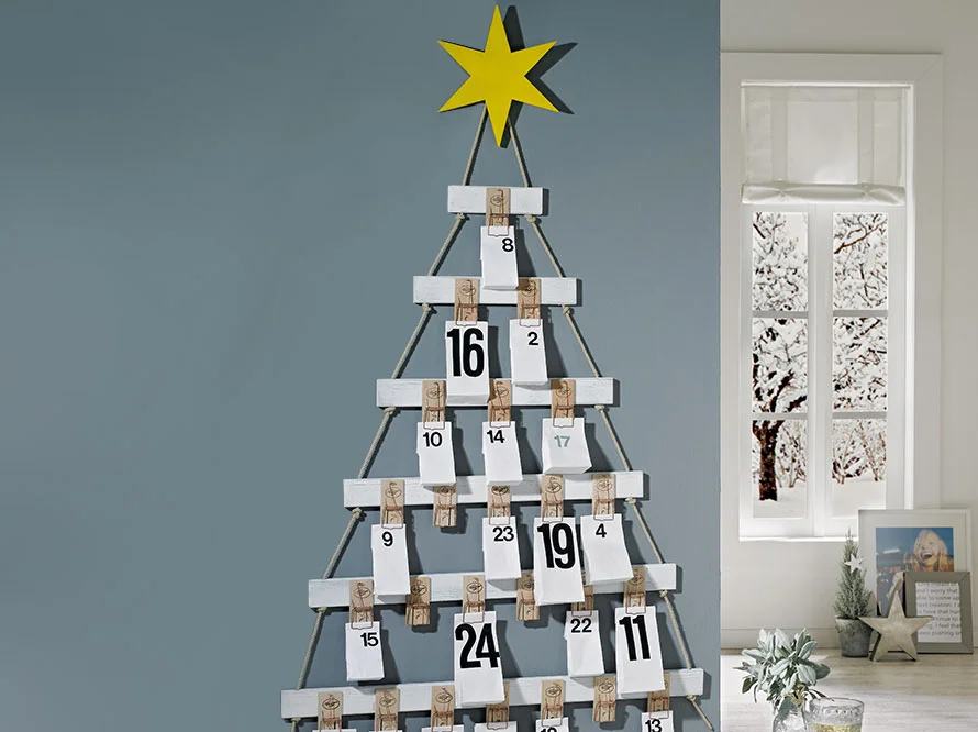 Ein Adventskalender in Form eines Tannenbaums mit weißen nummerierten Umschlägen.