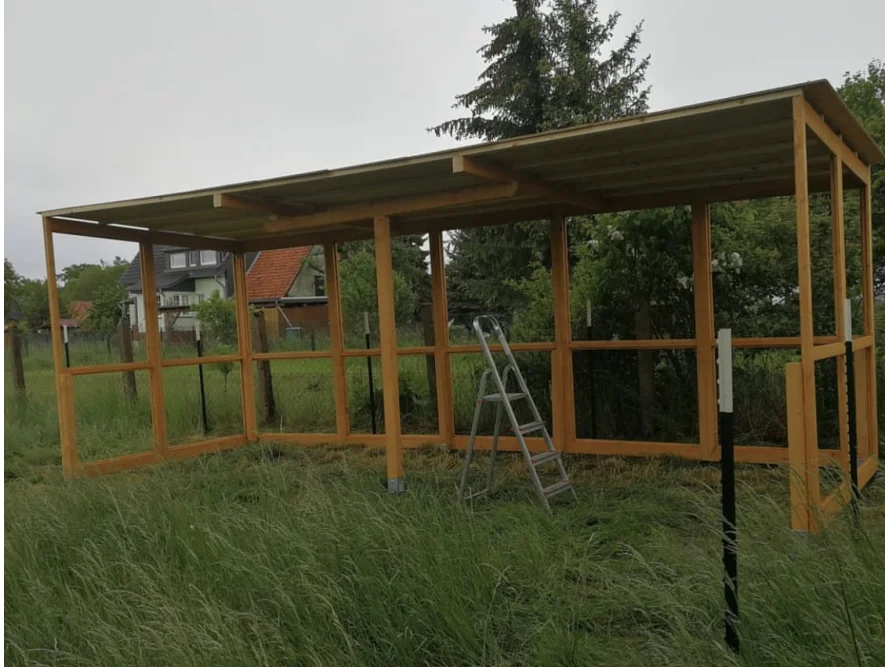 Unfertiger Holzstall mit einer Leiter darin.