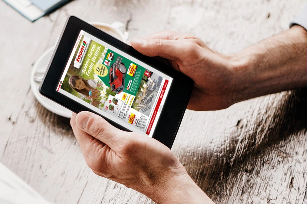 Eine Person hält ein Tablet in den Händen und schaut sich darauf einen digitalen Prospekt an.