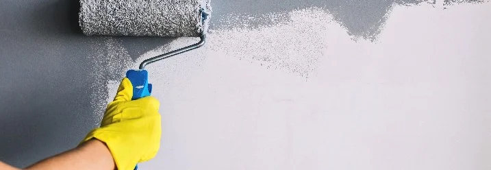 Hand mit Farbrolle streicht Wand weiß