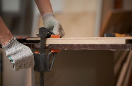 RT Moebel restaurieren Furnier 21 04 717x467 Furnier wird mit einer Schraubzwinge und einem Stück Holz festgedrückt