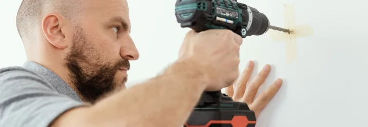 Person bohrt mit Akkuschrauber in Wand