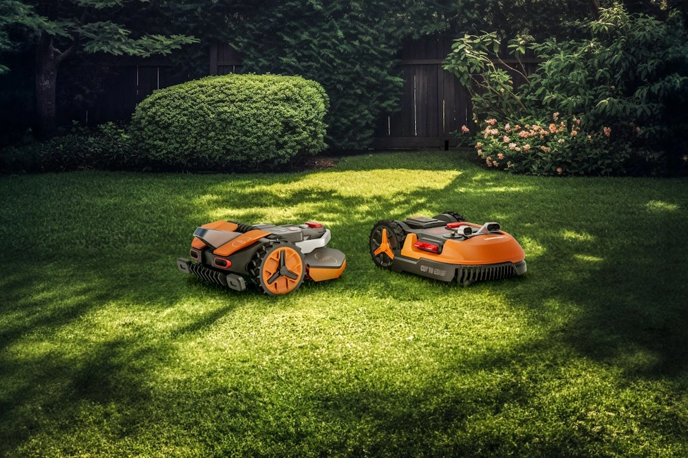 Zwei Mähroboter auf grünem Rasen