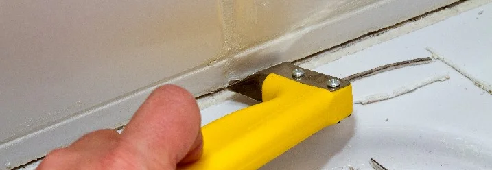 Hand entfernt Silikonfuge mit Werkzeug