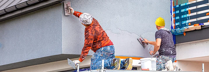 Zwei Personen verputzen Fassade