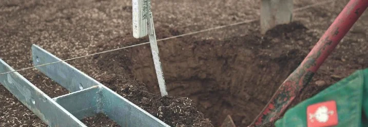 Person misst Tiefe eines Lochs mit Zollstock