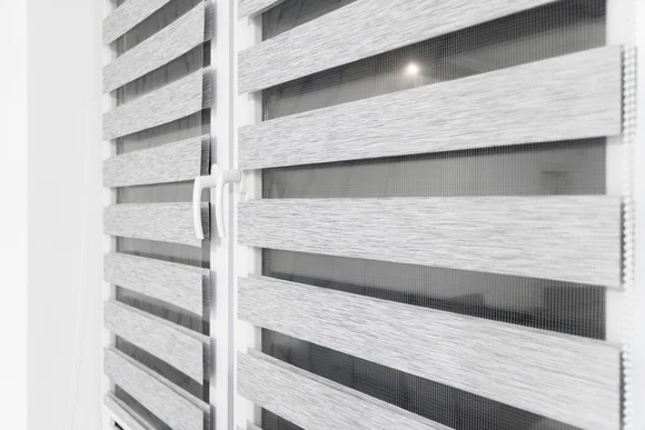 Grauer Doppelrollo vor einem Fenster