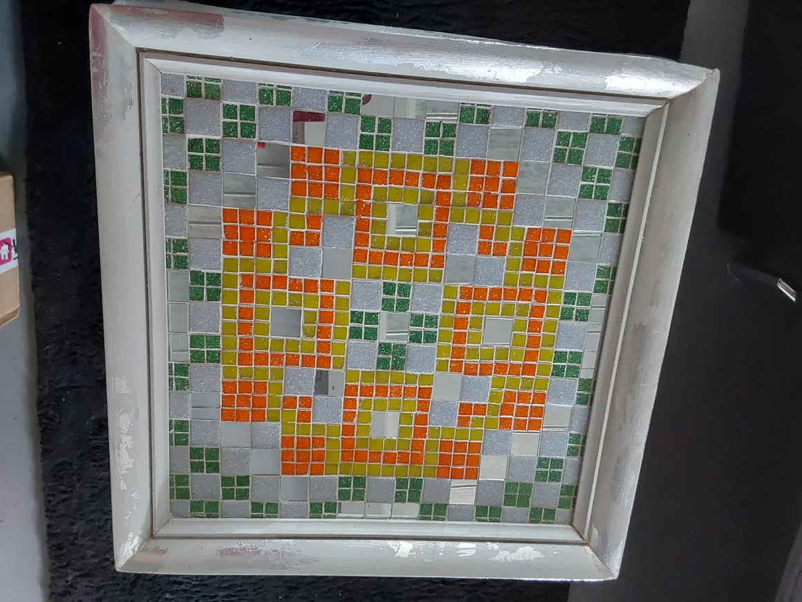 Geometrisches Mosaik aus bunten Fliesen in einem weißen Rahmen.
