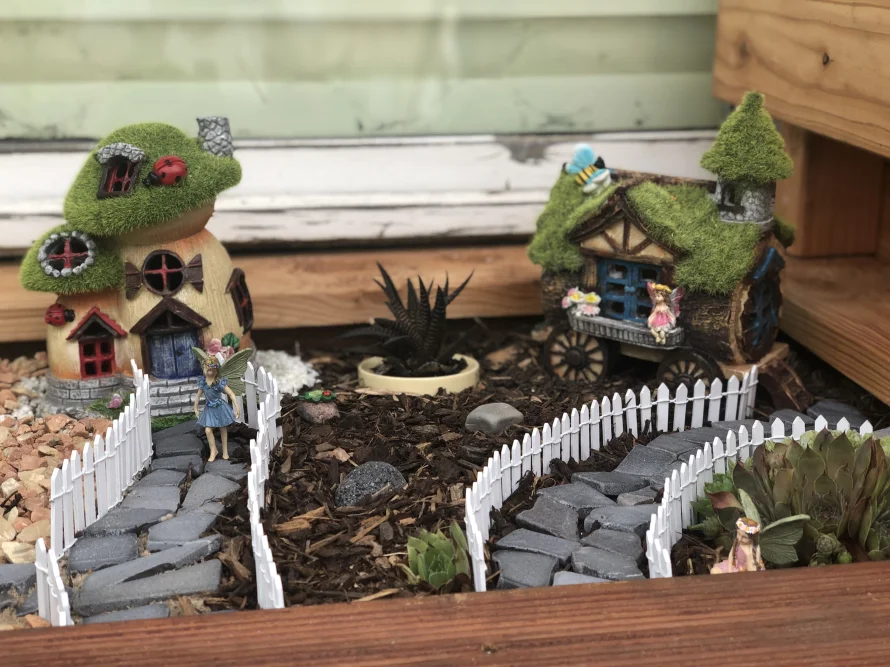 Ein Miniaturgarten mit Feenhäusern und -figuren.