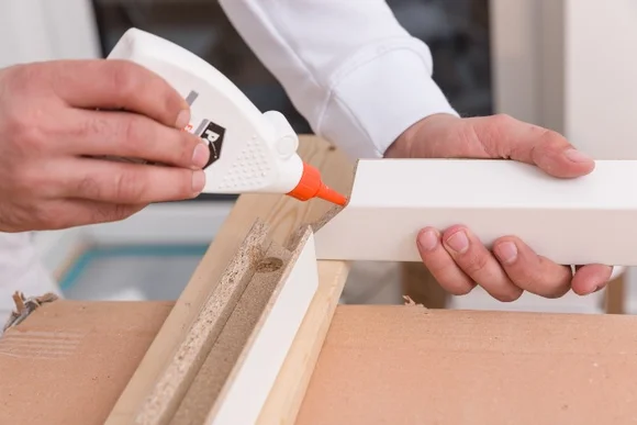 Person trägt Klebstoff auf Holz auf