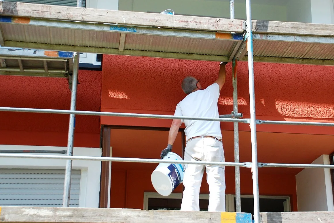 Person streicht Hauswand