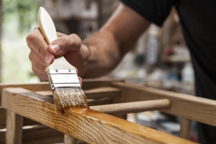 Person streicht Holz mit Pinsel