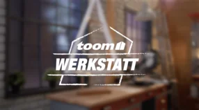 toom Werkstatt Logo mit unscharfem Weihnachtsbaum im Hintergrund