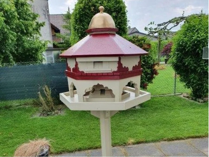 Verzierter Vogelfutterhäuschen auf einem Pfosten
