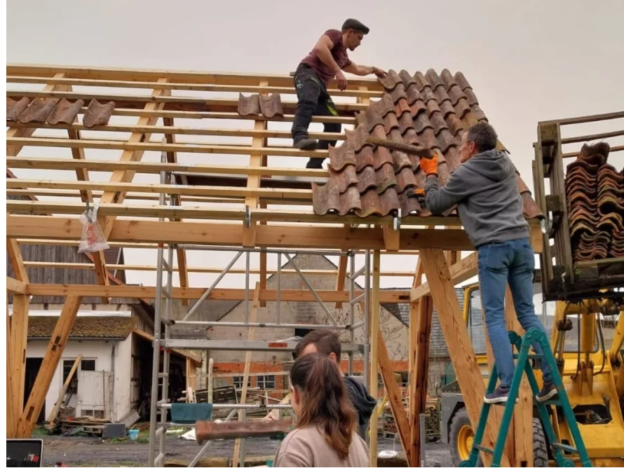 Personen decken ein Dach mit Ziegeln