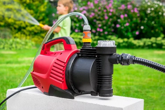 Rote Gartenpumpe mit angeschlossenem Schlauch