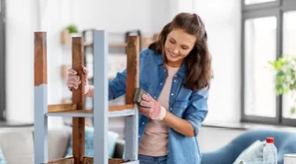 Person streicht Holztisch weiß.