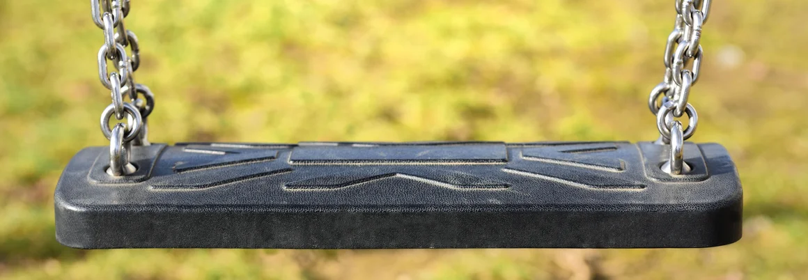 Leere schwarze Schaukel mit Ketten
