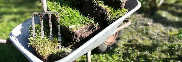 Schubkarre mit Grassoden und Grabegabel