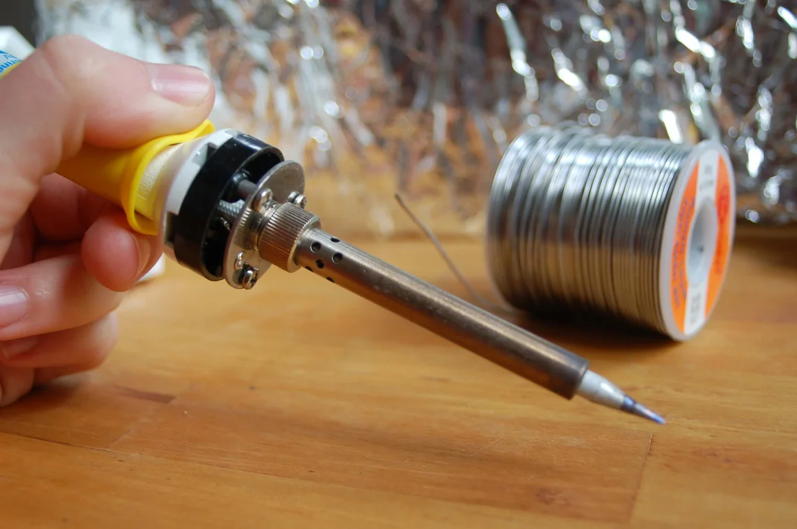 Hand hält einen Lötkolben