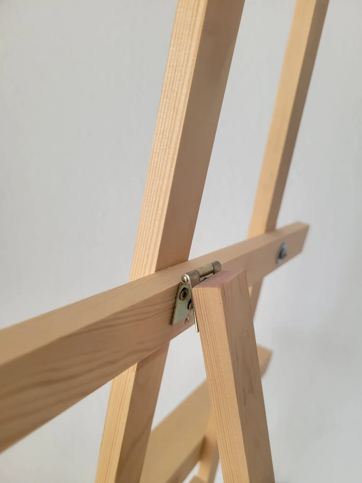 Nahaufnahme einer Staffelei aus hellem Holz mit einem Metallscharnier.