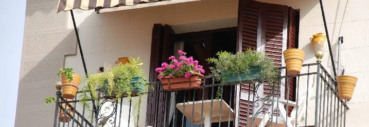 Ein Balkon mit einer gestreiften Markise und Blumentöpfen.