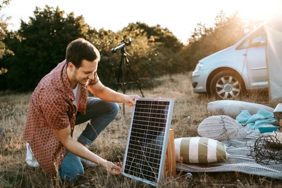 Eine Person stellt ein mobiles Solarmodul beim Campen auf.